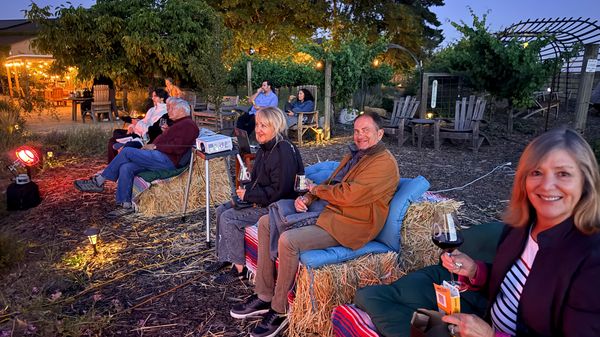 Guests watching a film on a large outdoor screen in the vineyard at dusk
